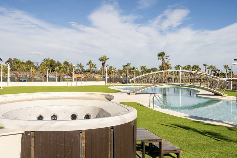Jacuzzi y piscina con puente en el jardín del residencial